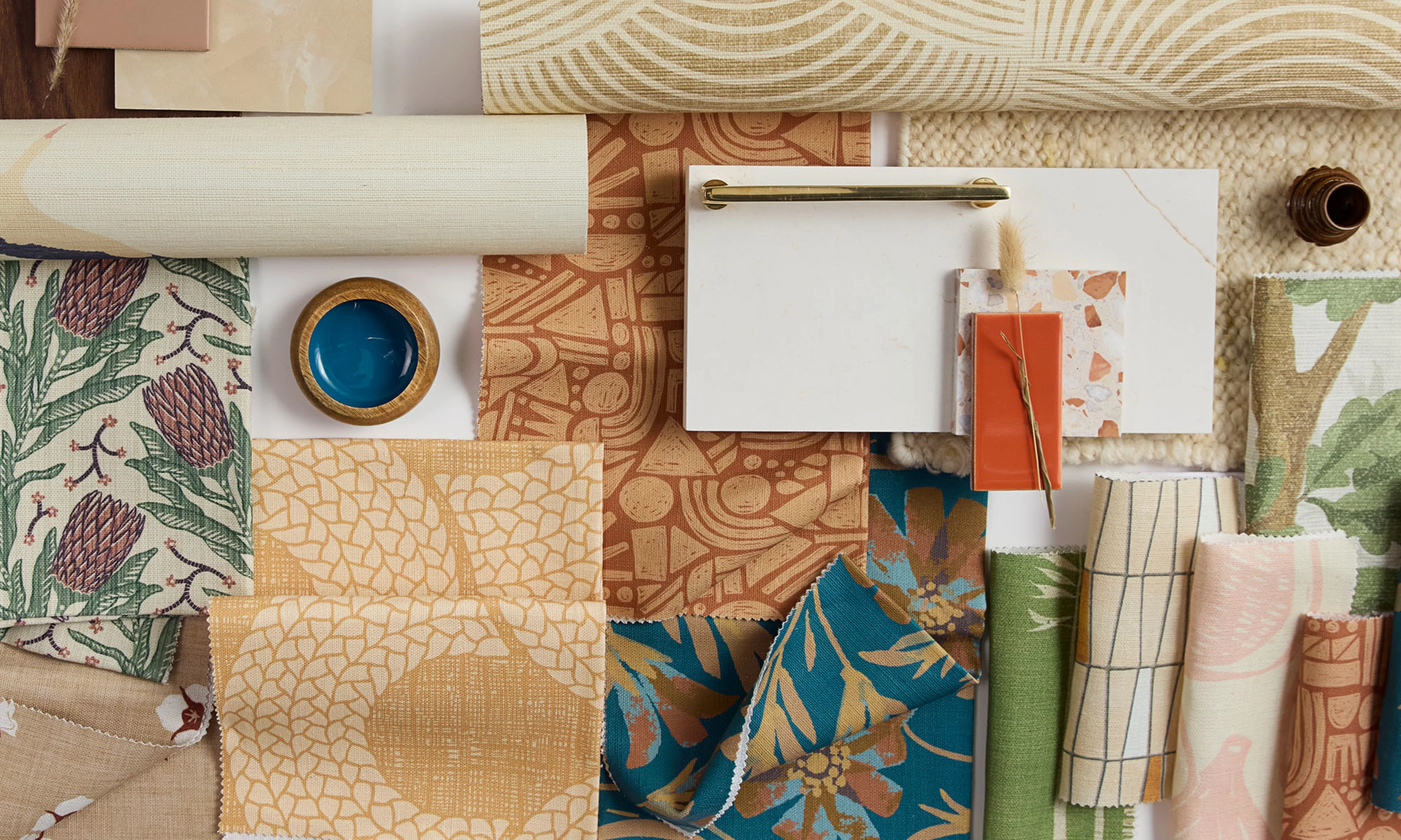 An assortment of elegant neutral wallpaper rolls and fabric samples with a contemporary safari aesthetic